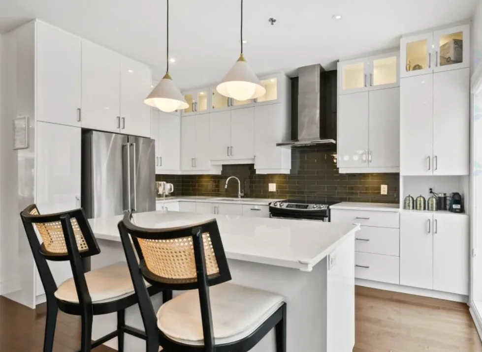 White Kitchen with Rattan Bar Stools and Dark Range Hood